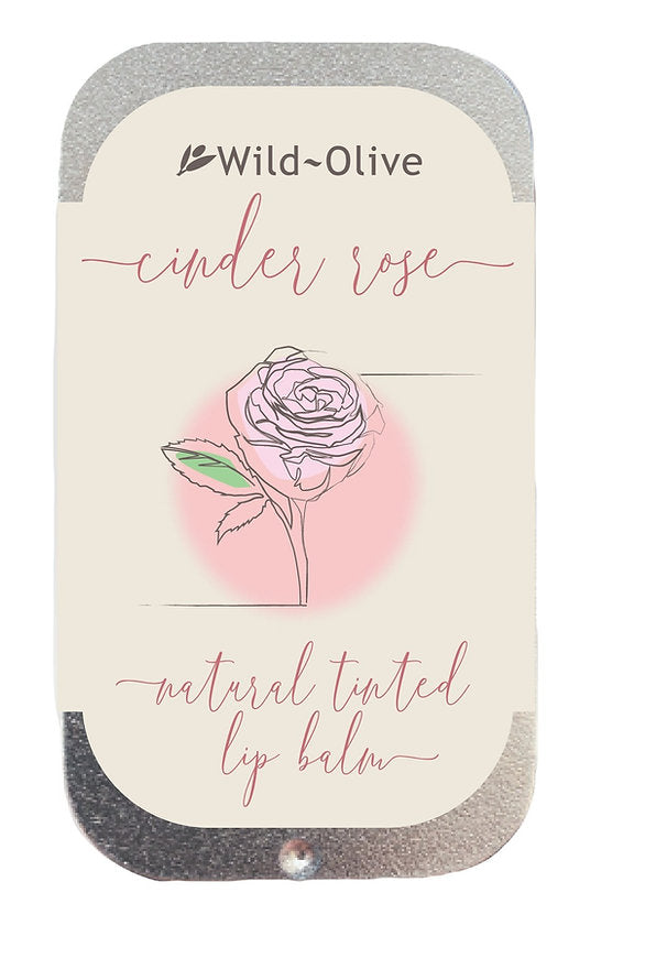 A tin of Wild-Olive Cinder Rose lip balm with a rose illustration and text indicating it's formulated with natural ingredients and 20 ml in size.