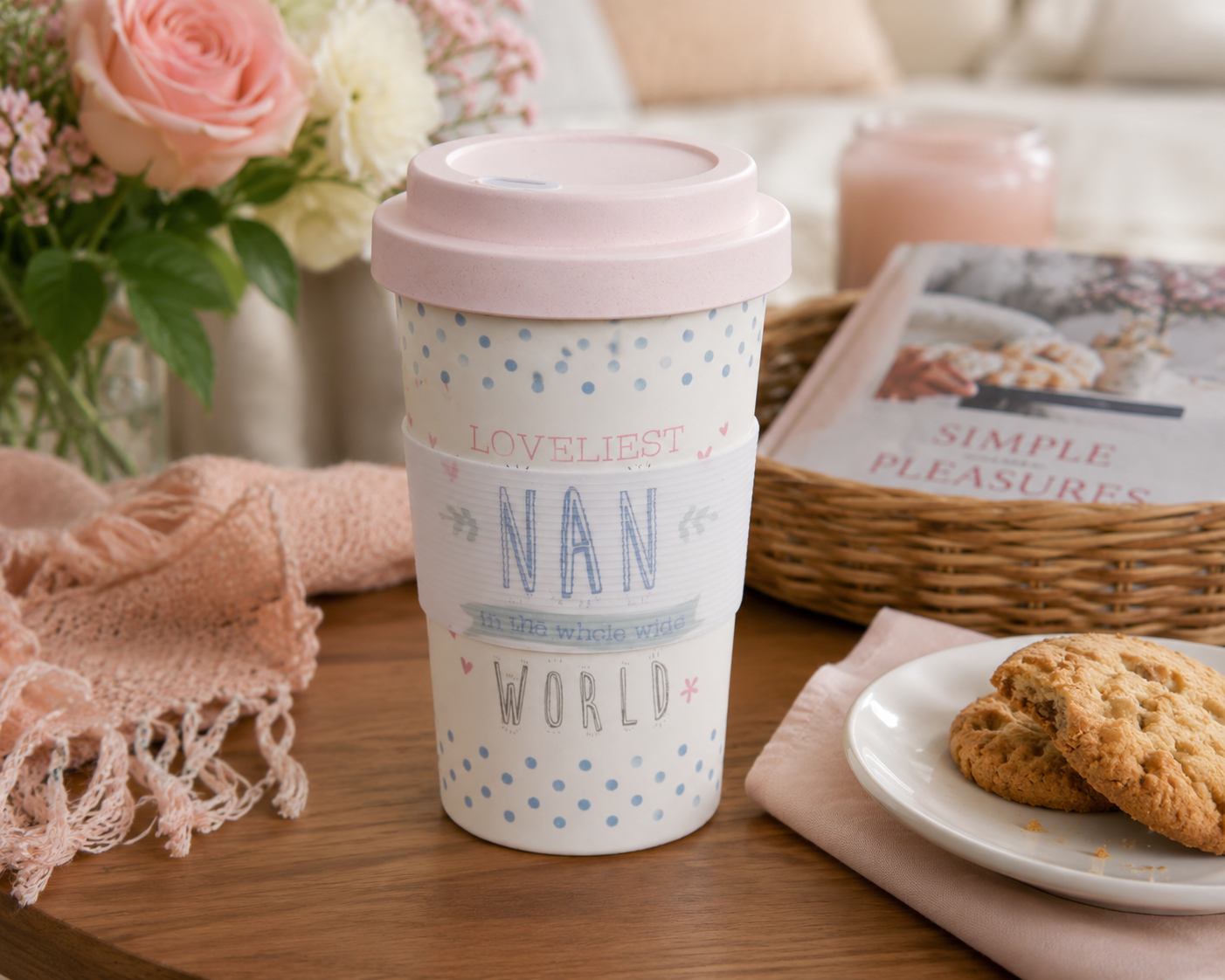 Travel mug with 'Loveliest Nan in the whole world' text on a table with cookies and flowers.